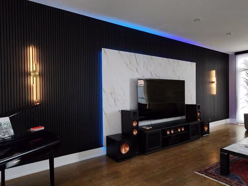 Backlit dark slatted wall panels framing a media wall in a Northbrook home