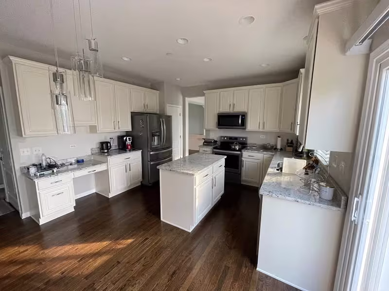 White kitchen with a compact island and black appliances in Villa Park