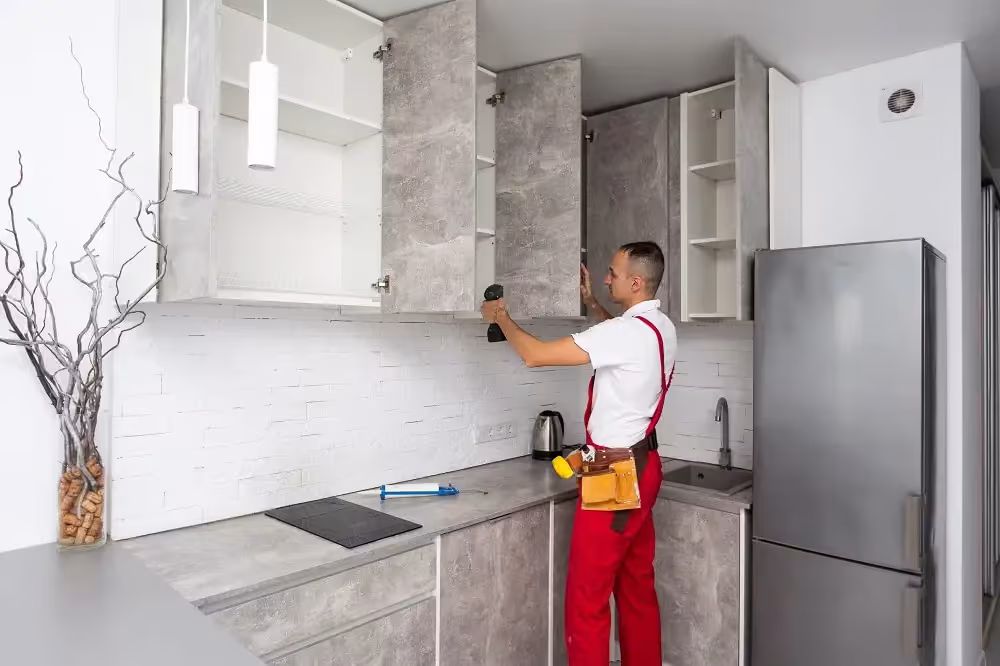 Installer fitting a concrete-look wall cabinet beside a fridge