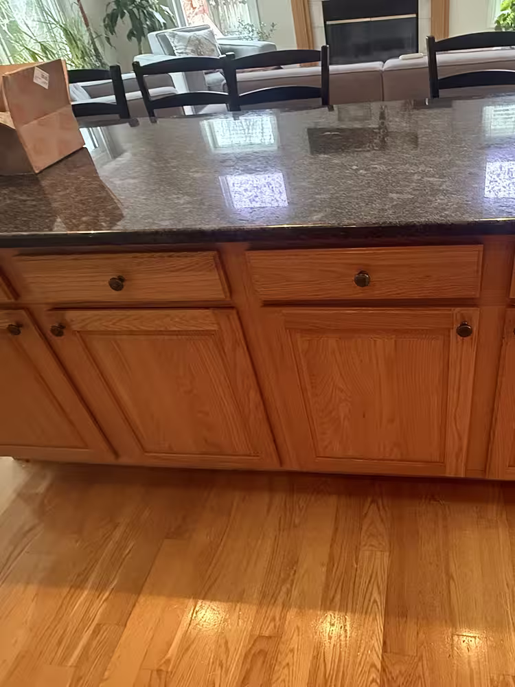 Honey oak open-plan kitchen with a dark granite island before refacing