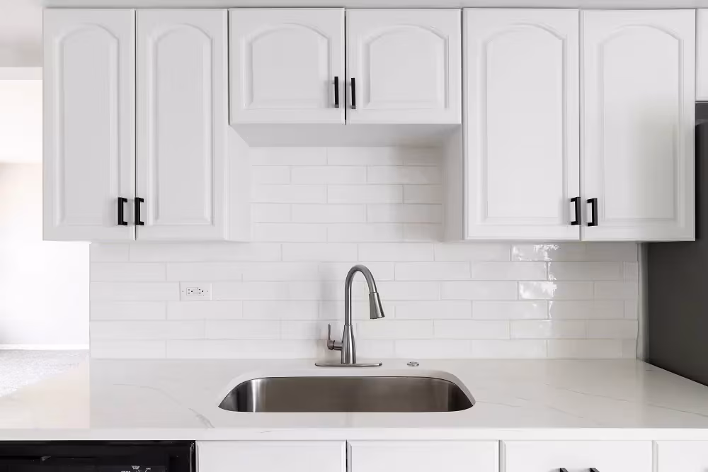 White arched cabinet doors with black knobs above the sink