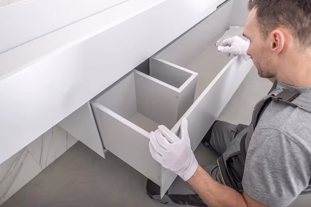 Technician in gloves fitting a white drawer box into a vanity cabinet