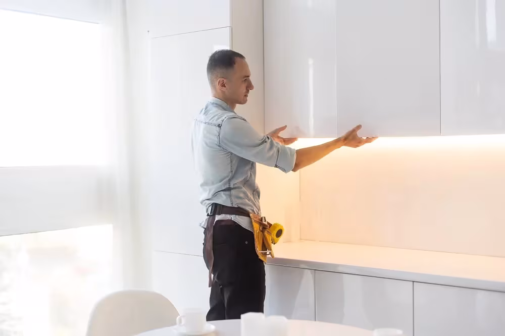 Worker smoothing a veneer sheet onto a wall cabinet