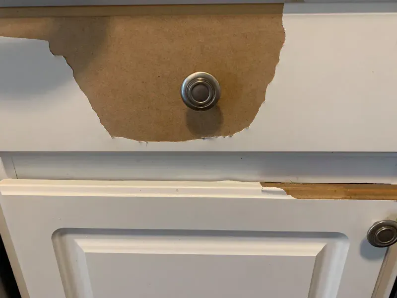 Thermofoil peeling back from a cabinet door around the knob