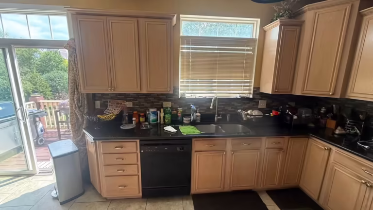 Maple base cabinets and black countertops along the window wall before refacing