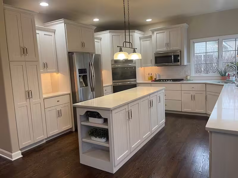 White refaced cabinets and an island with open shelving after the project