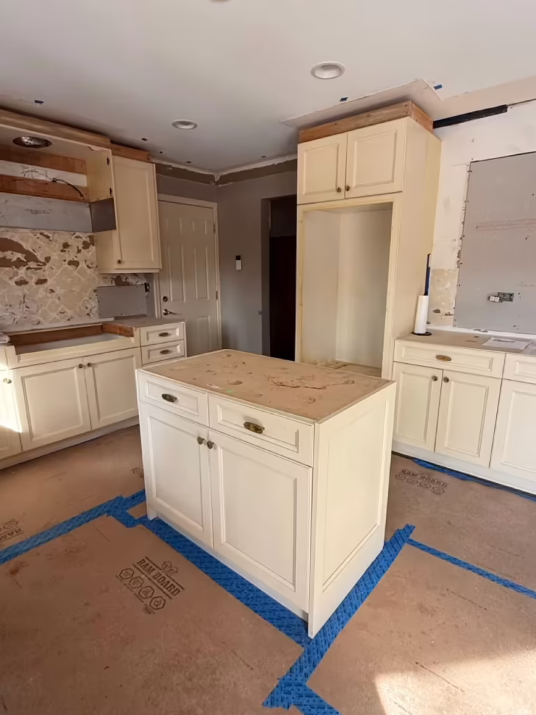 Cream raised panel cabinets and island taped off before charcoal refacing