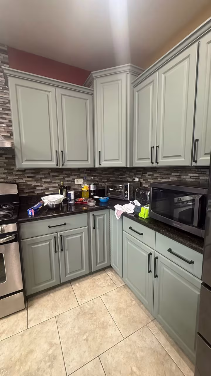 Refaced sage gray cabinetry around the range in the open-plan kitchen