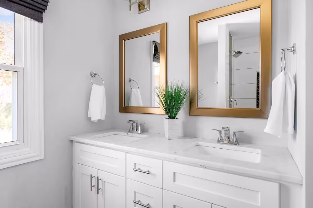 White double vanity with gold-framed mirrors in a bathroom