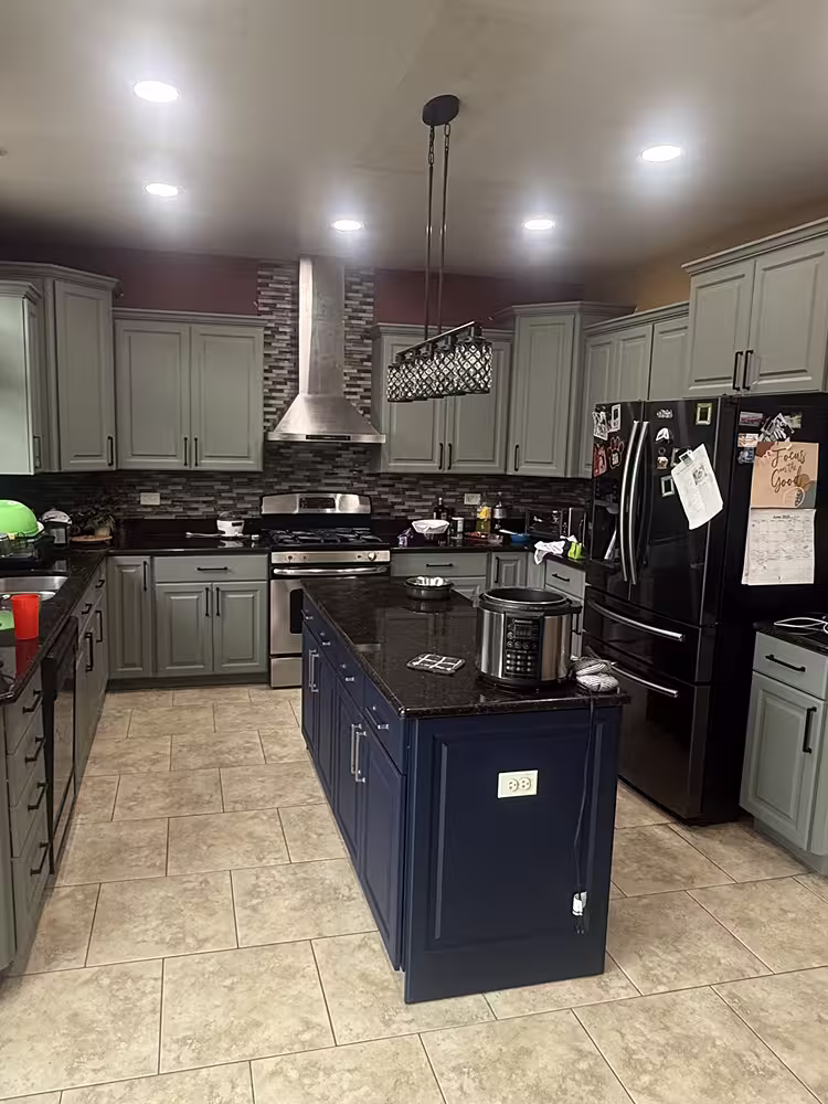 Sage gray raised panel cabinets with a navy island after refacing the maple kitchen