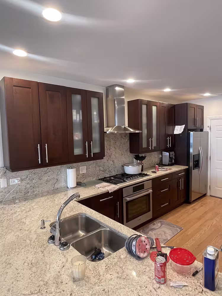 Dark espresso cabinets with glass-front uppers and granite counters before refacing