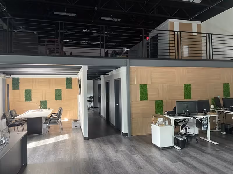 Open-plan office with green acoustic panels and desk pods