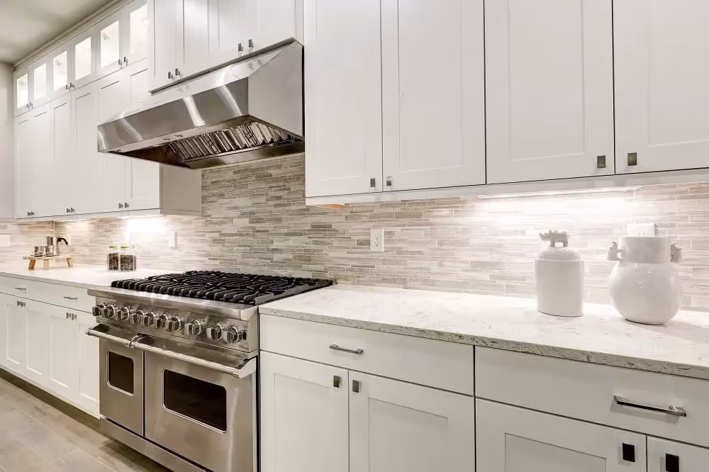 White kitchen with a professional range and marble backsplash