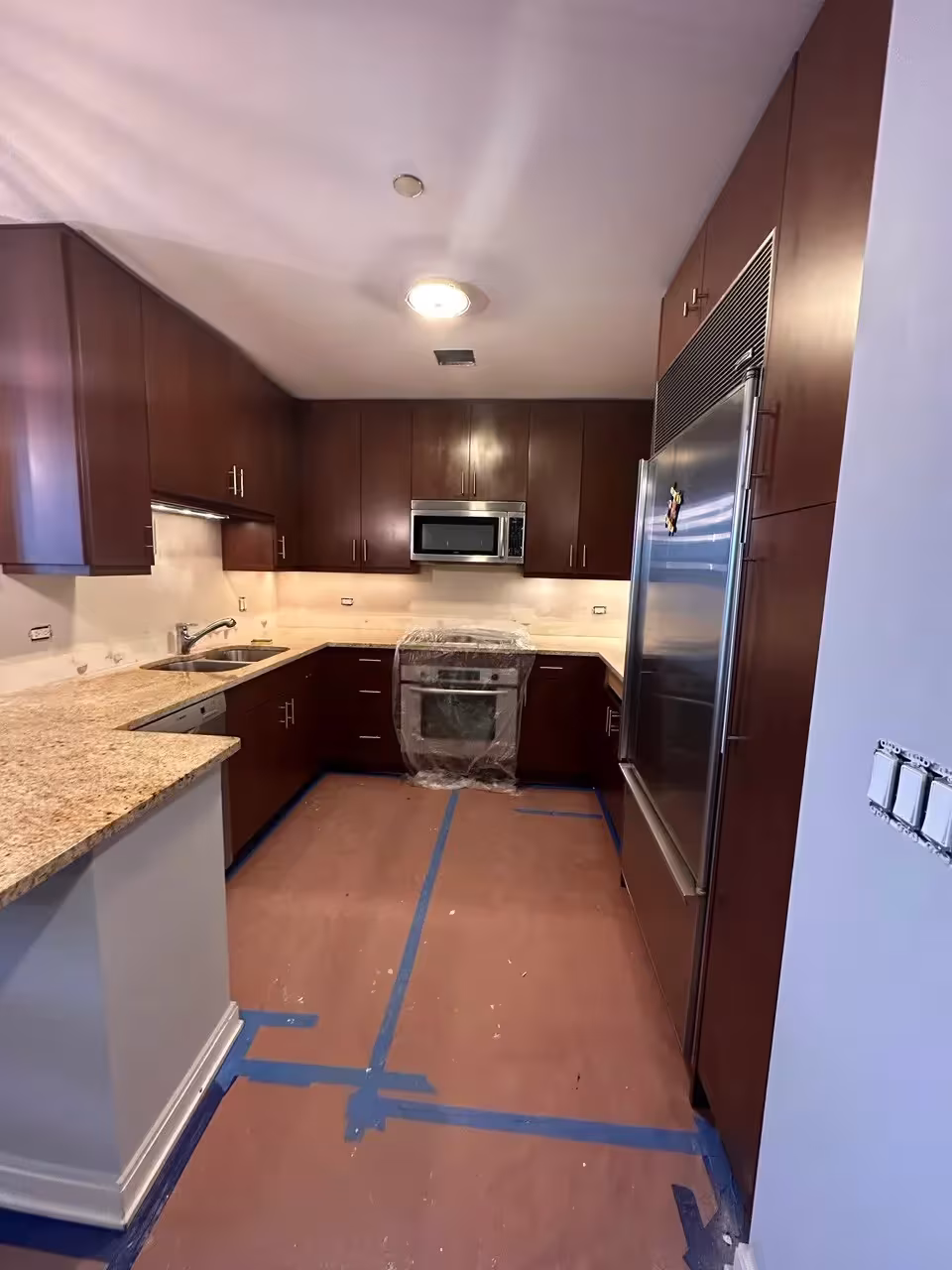 Dark cherry galley kitchen masked off before the refacing work starts