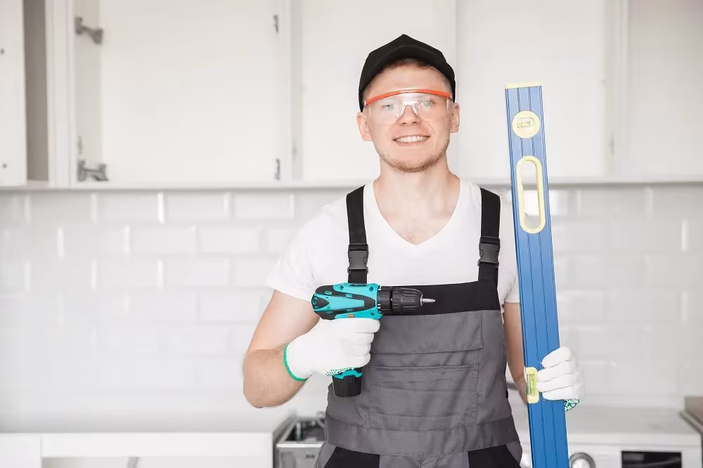 Estimator with a level and drill assessing a white kitchen