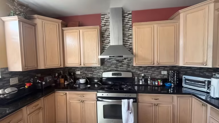 Light maple cabinets and a mosaic backsplash around the range before refacing
