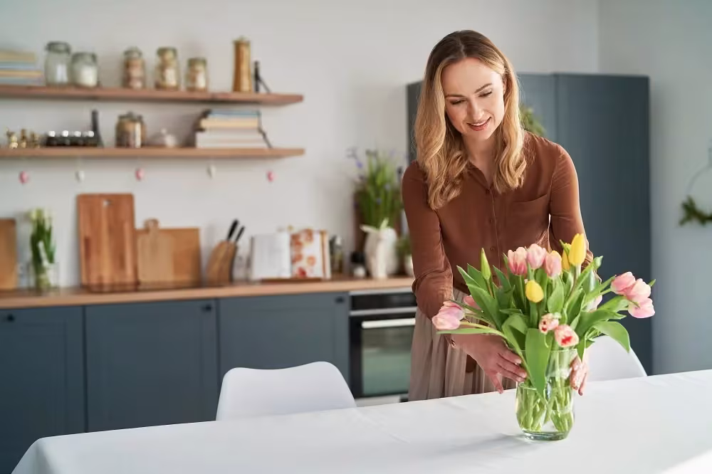 Woman arranging tulips in a teal and wood kitchen