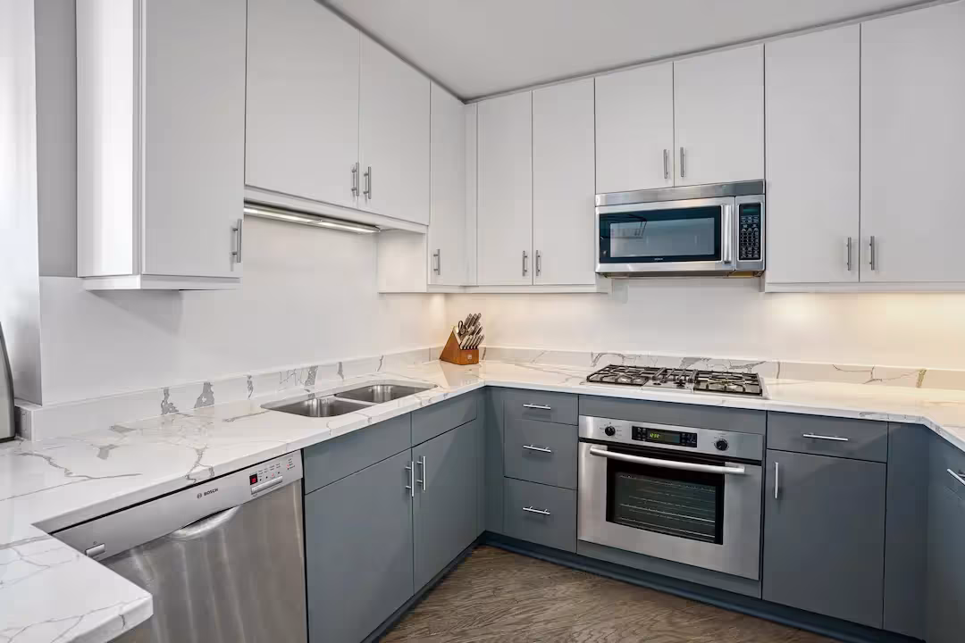 White upper cabinets above gray base units with a built-in oven