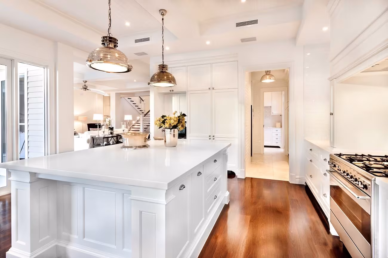 White kitchen with brass pendants over a marble island in Hanover Park