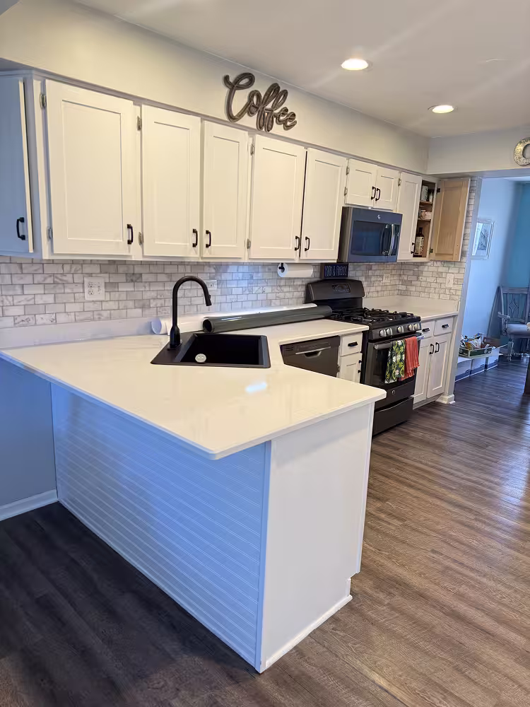 All-white refaced cabinets keeping the black hardware and subway tile backsplash in place