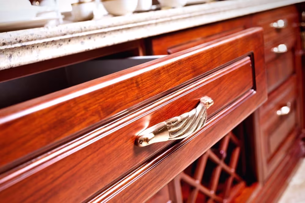 Cherry drawer front with an ornate brass pull on a modern thermofoil door
