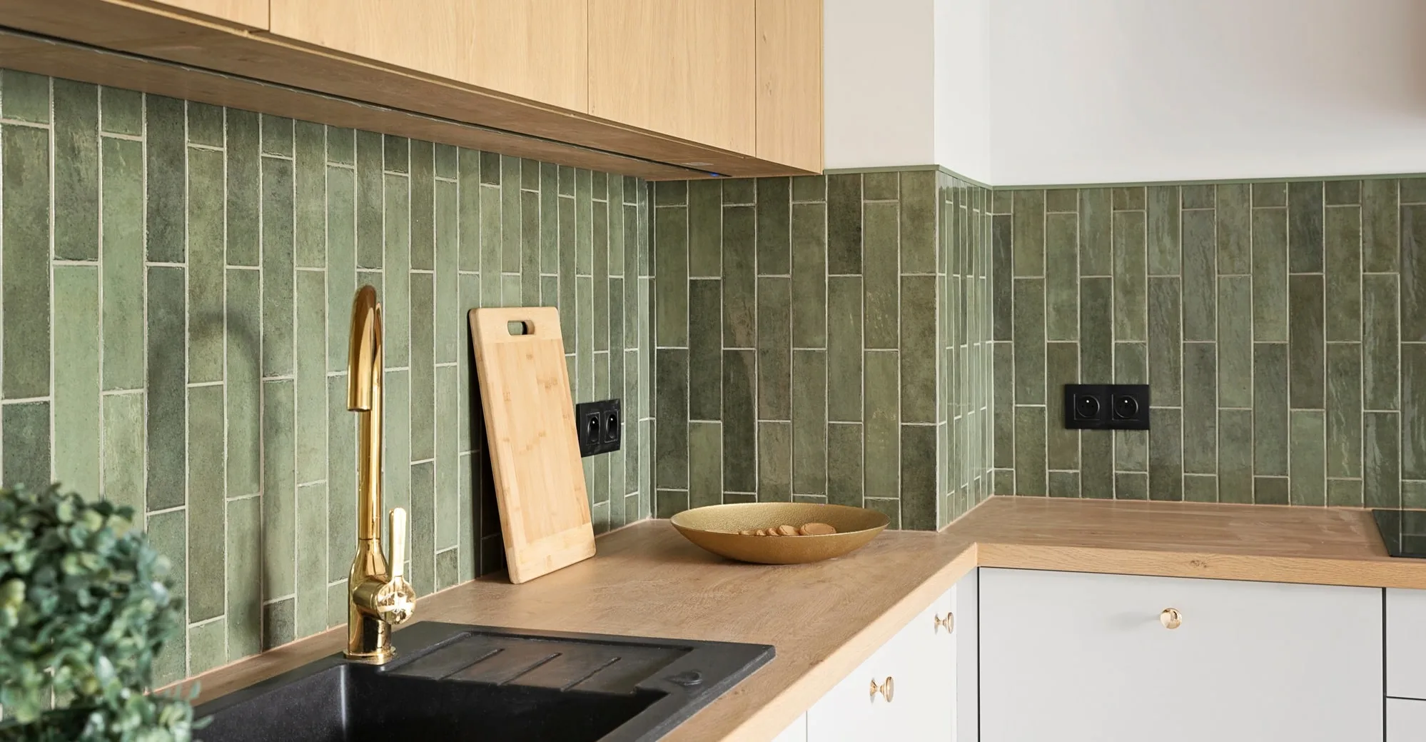 Green tile backsplash and a brass faucet above white cabinetry in Des Plaines