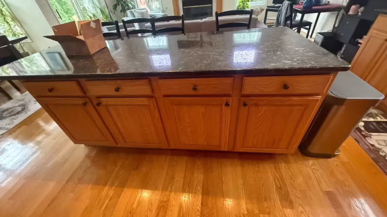 Honey oak island with a dark granite top before the open-plan kitchen was refaced