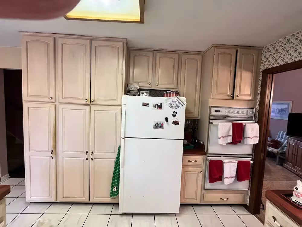 Pale blond cabinets and a white refrigerator in the Batavia kitchen before refacing