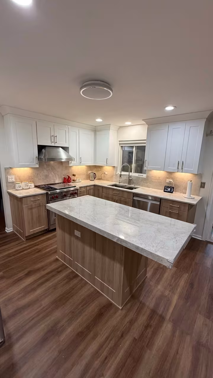 Custom wood island with a marble top at the centre of the refaced kitchen