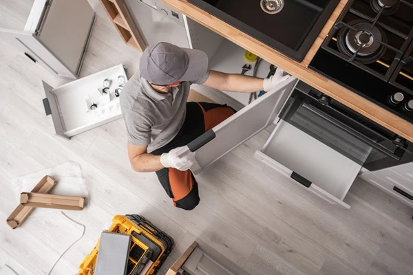Installer seen from above fitting base cabinets and the range