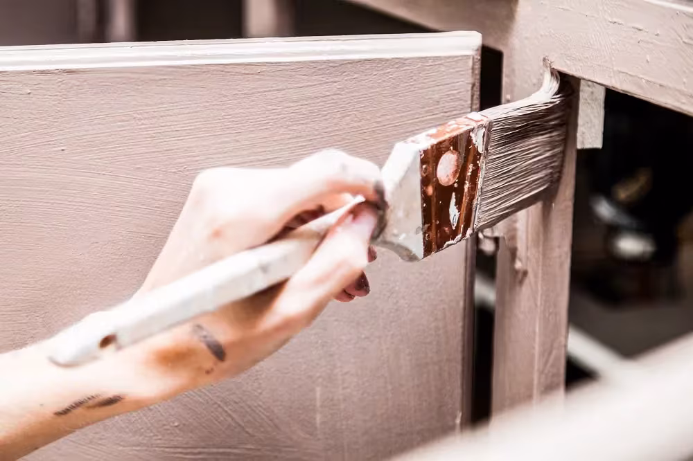 Hand rolling paint onto a cabinet door during a refinish