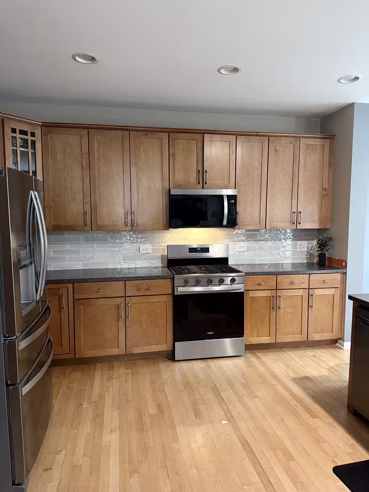 Light oak cabinets with gray countertops and subway tile before the refacing project