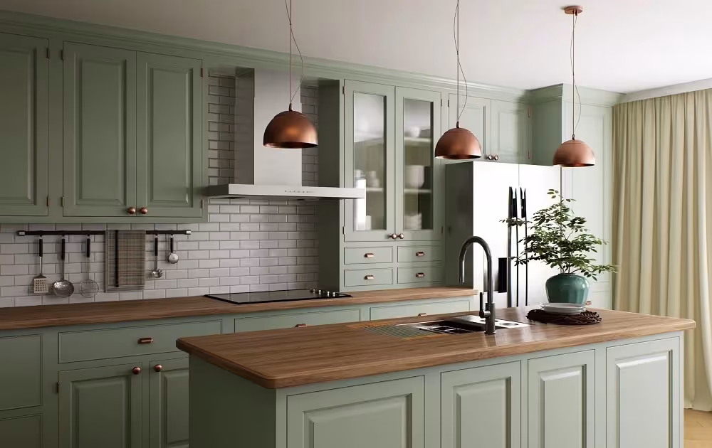Sage green cabinets with a wood counter and copper pendants