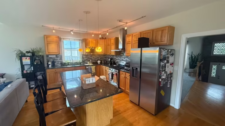 Open-plan honey oak kitchen with a dark granite island before beige linen refacing