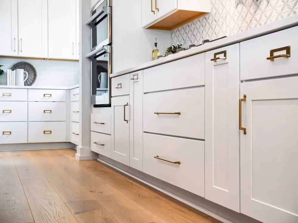 White Shaker cabinets with brass pulls and a patterned backsplash
