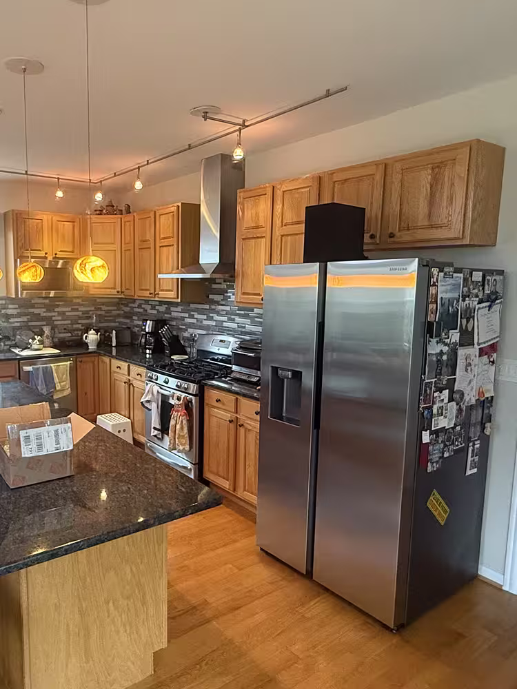 Honey oak open-plan kitchen with a dark granite island and track lighting before refacing