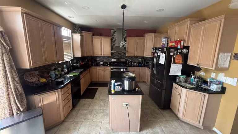 Light maple cabinets with black granite counters before the sage gray refacing