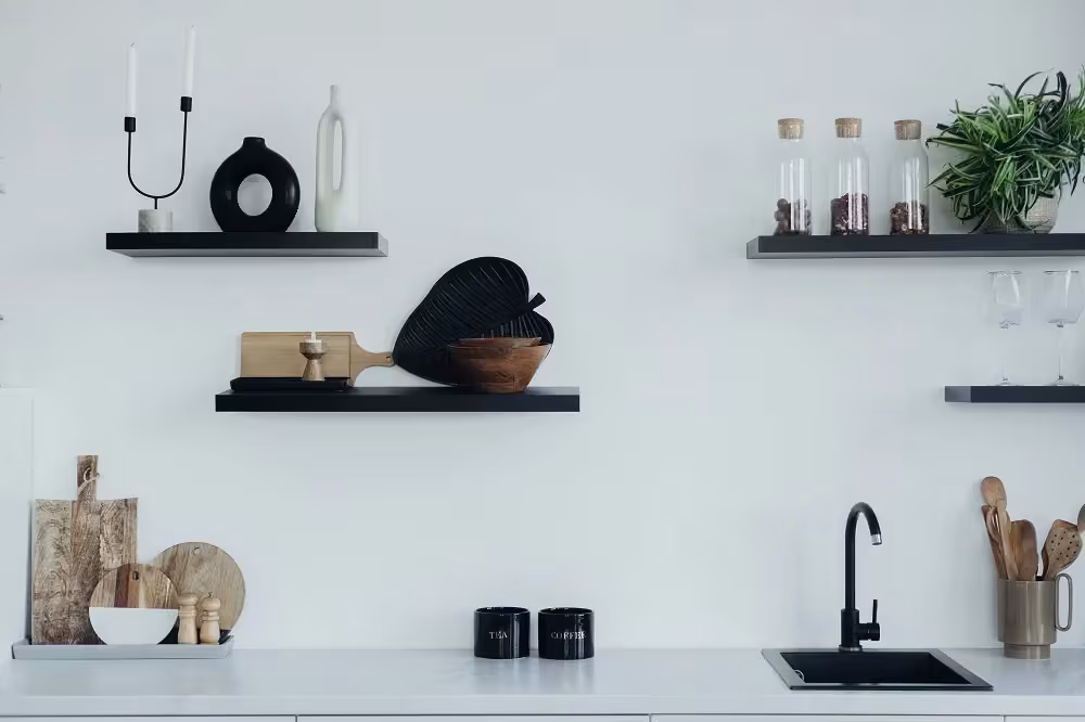 Black floating shelves styled with ceramics above a white counter