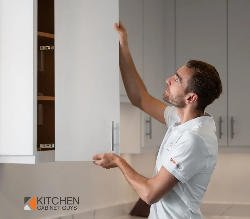 Kitchen Cabinet Guys technician fitting a refaced cabinet door in a home