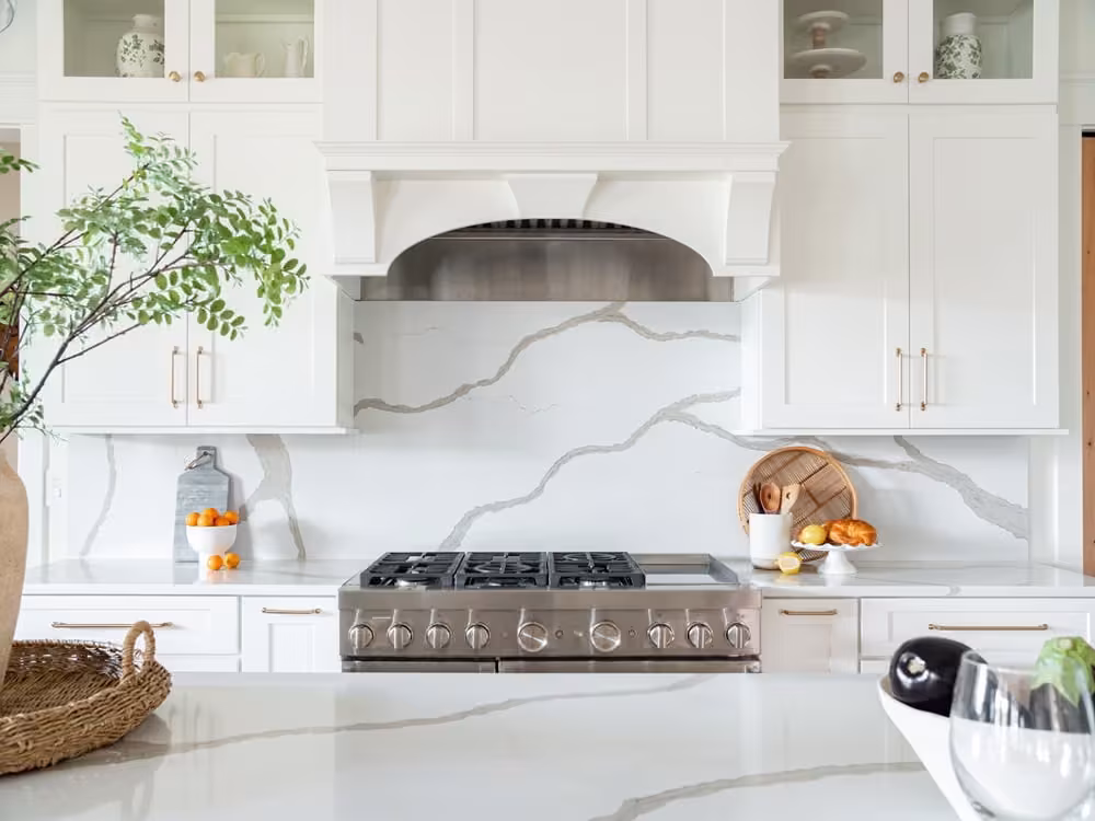 White kitchen with an arched range hood and a marble backsplash